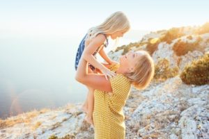 Mom playing with her child on top of the mountain in sunlight