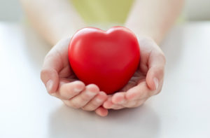 people, love, charity and family concept - close up of child hands holding red heart shape at home